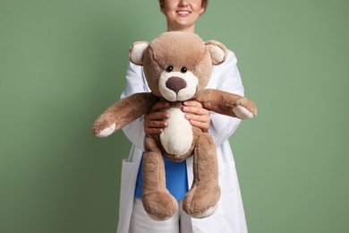 Photo of Pediatrician with toy bear on olive background, closeup