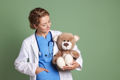 Photo of Pediatrician with toy bear on olive background. Space for text