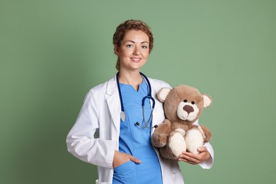 Photo of Pediatrician with toy bear on olive background