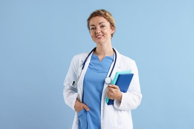 Photo of Portrait of professional pediatrician with stethoscope and notebooks on light blue background