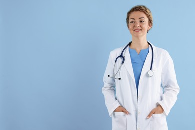 Photo of Portrait of professional pediatrician with stethoscope on light blue background. Space for text