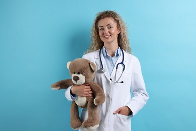 Photo of Pediatrician with toy bear on light blue background