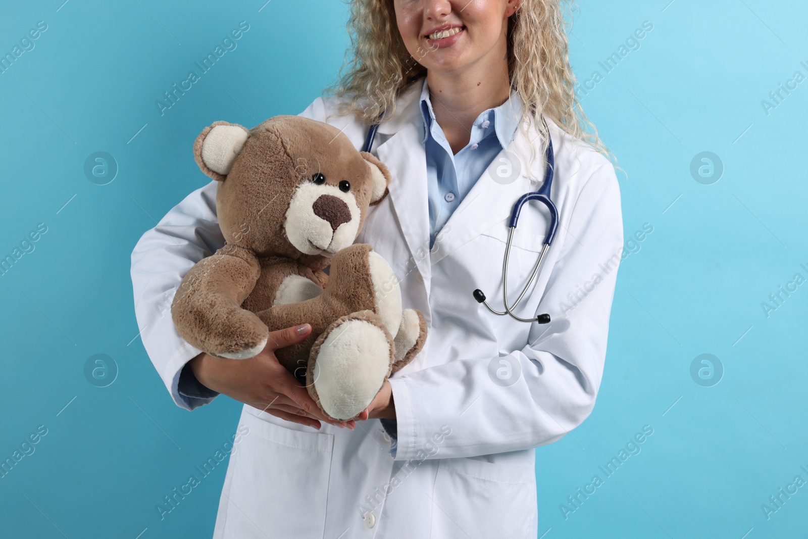 Pediatrician with toy bear on light blue background, closeup Photo of Pediatrician with toy bear on light blue background, closeup
