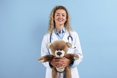 Photo of Pediatrician with toy bear on light blue background