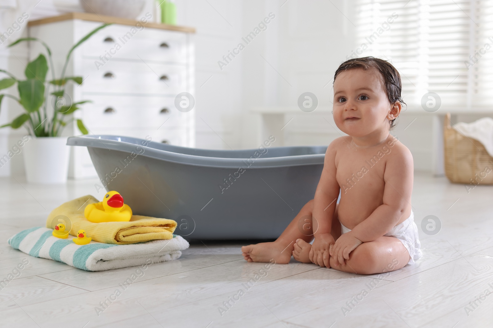 Cute little baby, towels and rubber ducks near bath at home Photo of Cute little baby, towels and rubber ducks near bath at home