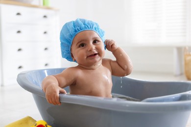 Photo of Cute little baby in cap bathing at home
