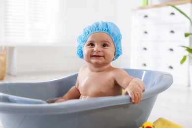 Photo of Cute little baby in cap bathing at home