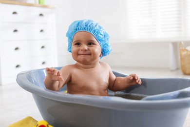 Photo of Cute little baby in cap bathing at home