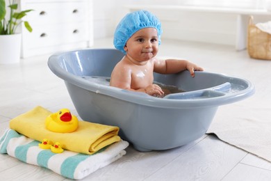 Photo of Cute little baby in cap bathing at home