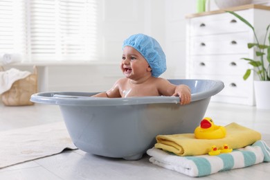 Photo of Cute little baby in cap bathing at home