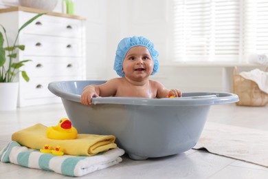 Photo of Cute little baby in cap bathing at home