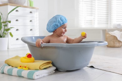 Photo of Cute little baby in cap bathing at home