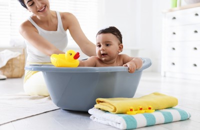 Photo of Mom bathing her little baby at home, closeup