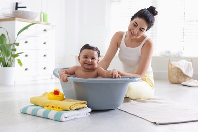 Photo of Mom giving bath to her little baby at home