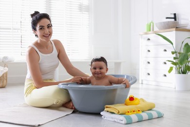Photo of Mom giving bath to her little baby at home