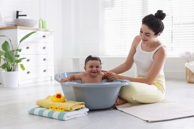 Photo of Mom giving bath to her little baby at home
