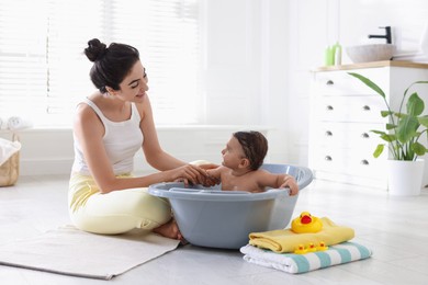 Photo of Mom giving bath to her little baby at home