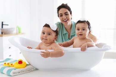 Photo of Mom bathing her twin children at home, selective focus
