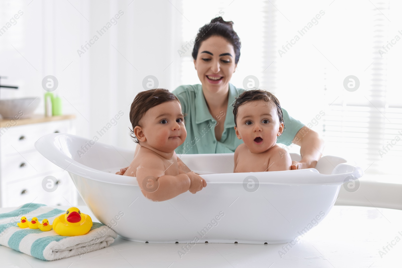 Mom bathing her twin children at home, selective focus Photo of Mom bathing her twin children at home, selective focus