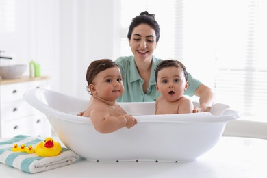 Photo of Mom bathing her twin children at home, selective focus