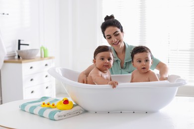 Photo of Mom bathing her twin children at home