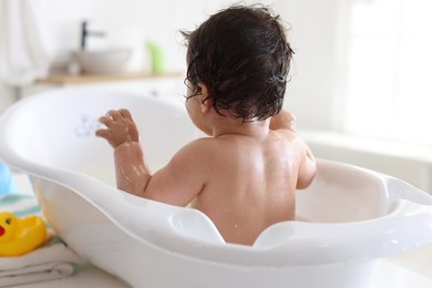Photo of Cute little baby bathing at home, back view