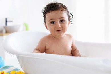 Photo of Cute little baby bathing in tub at home