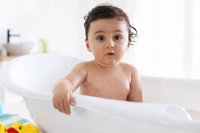 Photo of Cute little baby bathing in tub at home