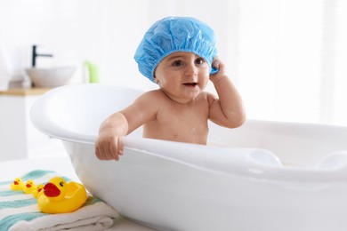 Photo of Cute little baby in cap bathing at home