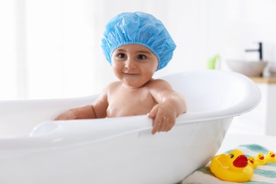 Photo of Cute little baby in cap bathing at home