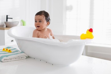 Photo of Cute little baby bathing in tub at home