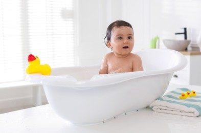 Photo of Cute little baby bathing in tub at home