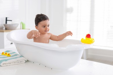 Photo of Cute little baby bathing in tub at home