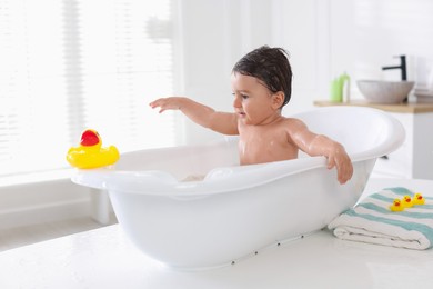 Photo of Cute little baby bathing in tub at home
