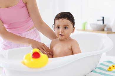Photo of Mom bathing her little baby at home, closeup