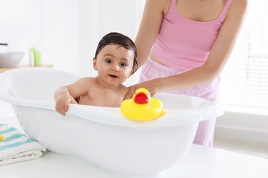 Photo of Mom bathing her little baby at home, closeup