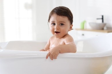 Photo of Cute little baby bathing in tub at home