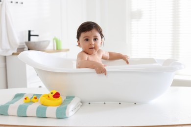 Photo of Cute little baby bathing in tub at home