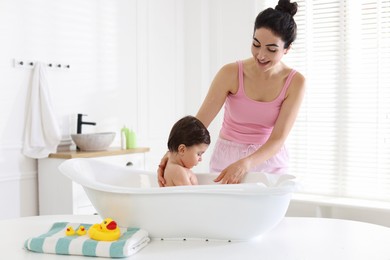 Photo of Mom giving bath to her little baby at home