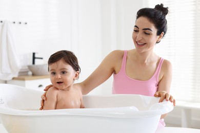Photo of Mom giving bath to her little baby at home