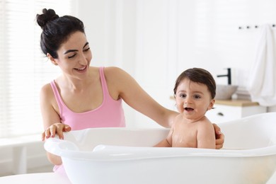 Photo of Mom giving bath to her little baby at home