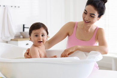 Photo of Mom giving bath to her little baby at home