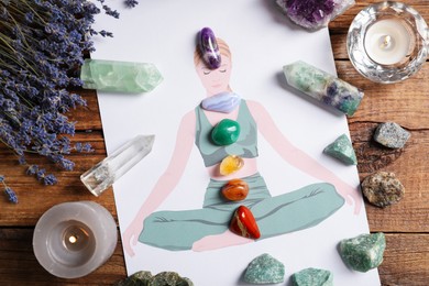 Photo of Human drawing with gemstones placed on chakras, lavender flowers on wooden table, flat lay