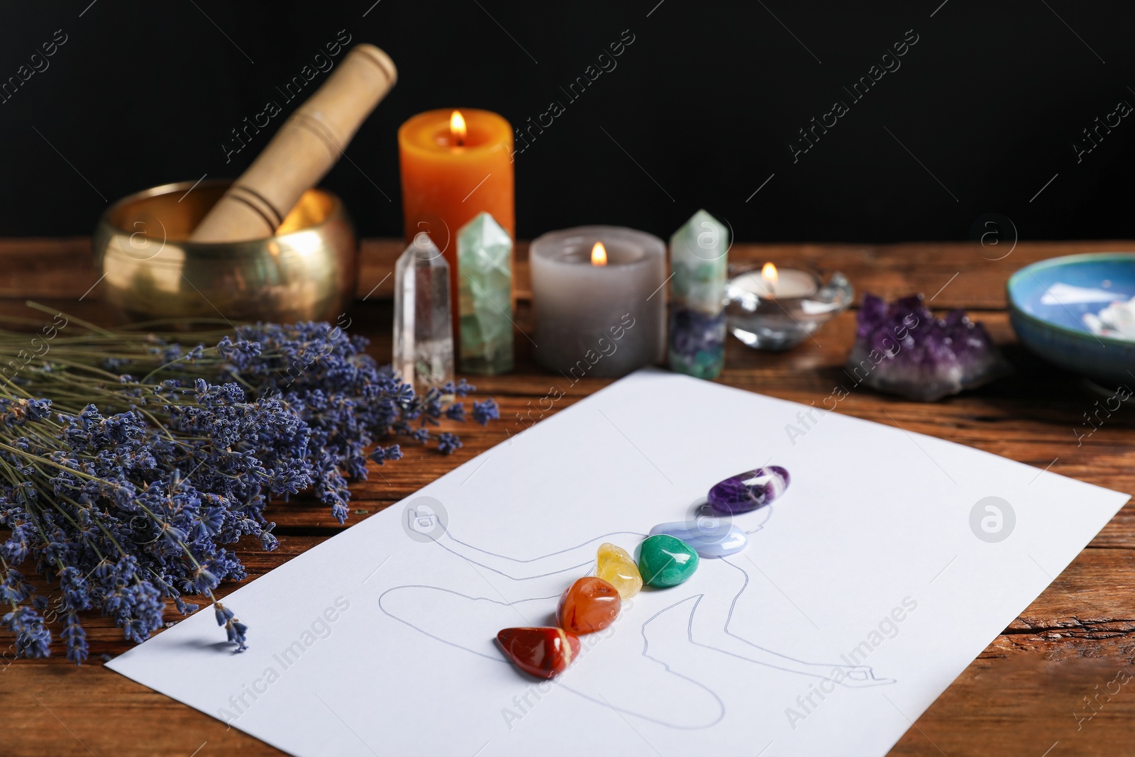 Human drawing with gemstones placed on chakras, lavender flowers on wooden table, closeup Photo of Human drawing with gemstones placed on chakras, lavender flowers on wooden table, closeup