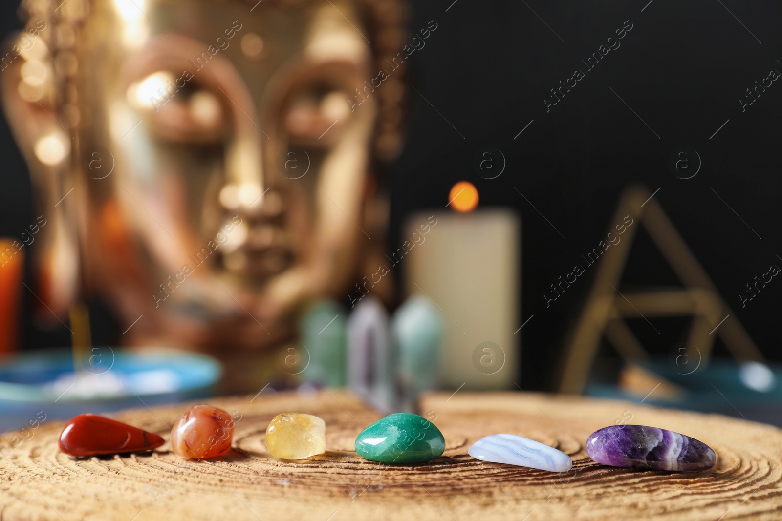 Chakra gemstones on table with candles and Buddha figure, selective focus Photo of Chakra gemstones on table with candles and Buddha figure, selective focus