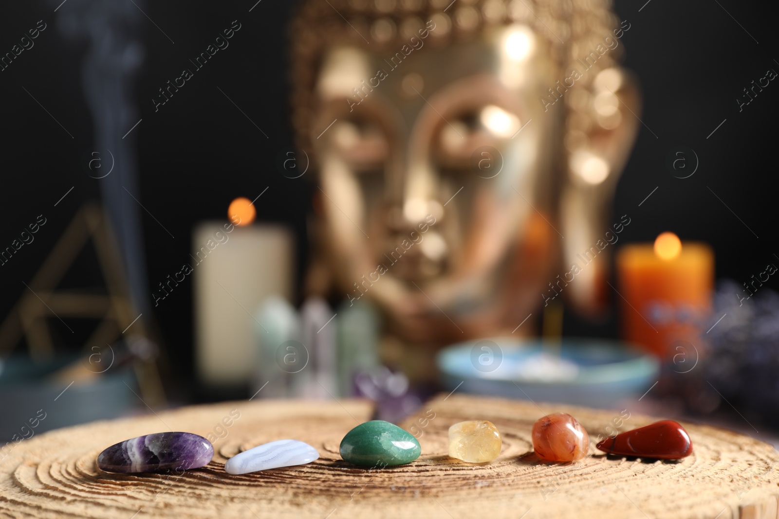 Chakra gemstones on table with candles and Buddha figure, selective focus Photo of Chakra gemstones on table with candles and Buddha figure, selective focus