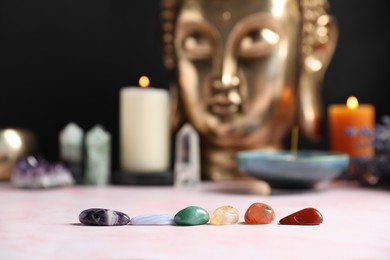 Photo of Chakra gemstones on table with candles and Buddha figure, selective focus