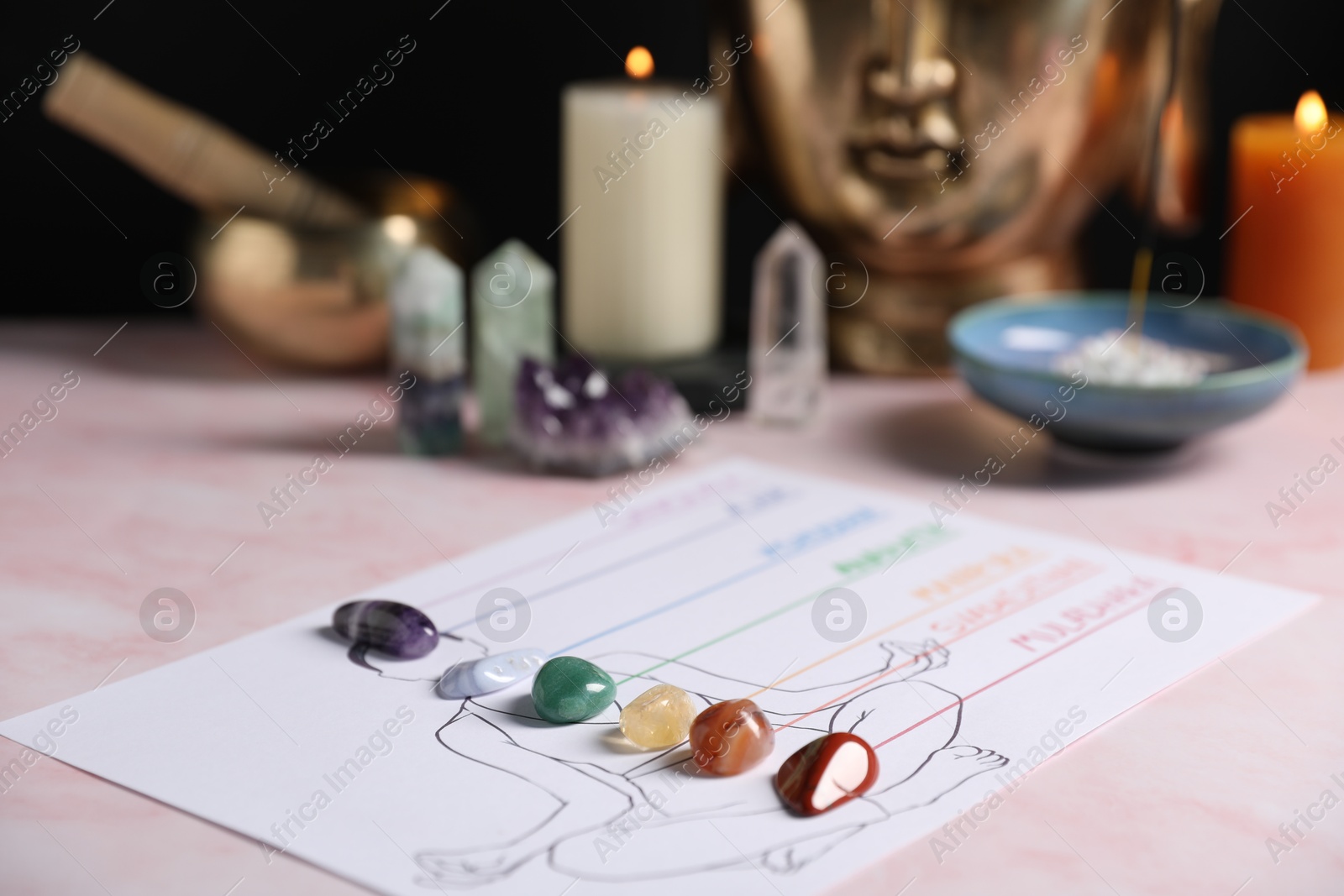 Human drawing with gemstones placed on chakras on light pink table, closeup Photo of Human drawing with gemstones placed on chakras on light pink table, closeup