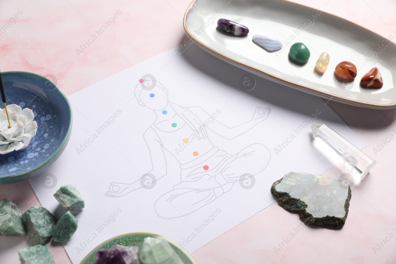 Drawing of chakras on human body, gemstones, incense on light pink table, closeup Photo of Drawing of chakras on human body, gemstones, incense on light pink table, closeup