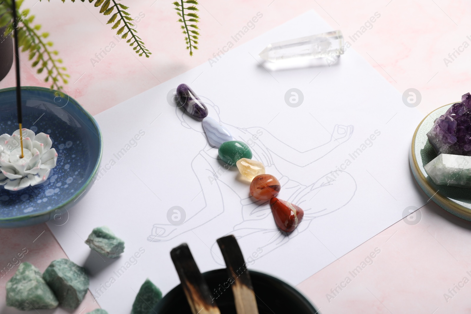 Human drawing with gemstones placed on chakras, incense and palo santo against light background, closeup Photo of Human drawing with gemstones placed on chakras, incense and palo santo against light background, closeup